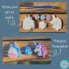 Unpainted unicorn and rose-shaped craft pieces with small paint pots and brushes