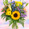 Mixed bouquet with sunflowers, lilies, and purple daisies in a glass vase