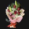 Bouquet of red roses, pink carnations, and white lilies wrapped in pink paper