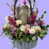 Basket arrangement with an angel statue, pink and white flowers, and greenery