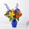 Bouquet of orange roses and yellow lilies in a blue glass vase