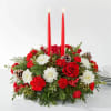 Holiday centerpiece with red candles, roses, carnations, and white daisies