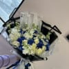 Bouquet of white roses and blue hydrangeas wrapped in black and clear paper