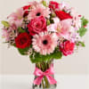 Pink and red mixed bouquet in a clear glass vase with a pink ribbon
