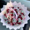 Bouquet of pink and burgundy roses with baby's breath and a pink ribbon