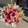Bouquet of pink and red roses with lilies wrapped in white paper