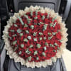 Large bouquet of red roses wrapped in beige paper with eucalyptus accents