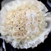 Round bouquet of cream roses wrapped in white tissue paper