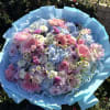 Large pastel bouquet of pink, blue, and white flowers wrapped in blue paper
