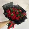 A bold cluster of twenty red roses arranged in a tight, rounded