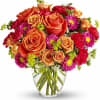 Orange roses and pink daisies in a clear glass vase