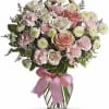 Pink and white rose bouquet in a glass vase with a pink ribbon
