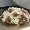 Round bouquet of white and tan roses tied with a pink ribbon