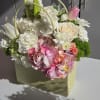 Mixed flower arrangement in a pale green gift bag with pink and white blooms