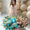 Large pastel flower basket with a BABY sign and a child standing behind it
