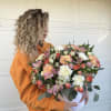 Large mixed bouquet in a white hatbox held by a woman