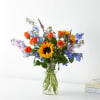 Mixed bouquet with a sunflower and orange roses in a clear glass vase