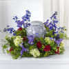 Purple and red floral arrangement around a gray urn