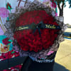Large bouquet of red roses with a black ribbon and Spanish text