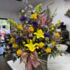 Tall mixed bouquet in a woven basket with pink ribbon and yellow lilies