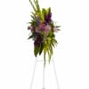 Tall floral standing spray with purple and green flowers on a white easel