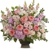 Pink roses and mixed pastel flowers arranged in a dark vase