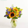 Sunflower bouquet in a clear glass vase with purple and yellow accents