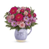 Pink and lavender flowers arranged in a lavender pitcher vase