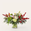Arrangement of white lilies, roses, and red berry branches in a glass vase