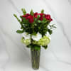 Red roses and white orchids arranged in a tall glass vase