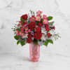 Red and pink mixed bouquet in a pink glass vase