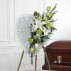 Heart-shaped floral spray on an easel beside a casket