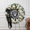 White floral funeral wreath with a Raiders emblem and black ribbon