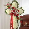 Dense white carnations shaped into a dignified standing cross create a solemn