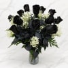 Black roses with white baby's breath in a clear glass vase