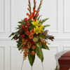 Standing floral spray with red, orange, and yellow flowers on an easel