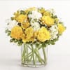 Yellow roses and white flowers arranged in a clear glass vase.