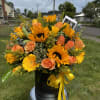Bouquet of sunflowers and peach roses in a black hatbox with yellow ribbon