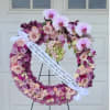 Heart-shaped floral wreath with pink roses and orchids on an easel