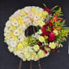 Large floral wreath with cream, yellow, pink, and red flowers on an easel