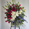 Standing floral spray with red roses, white lilies, and blue flowers