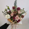 Mixed bouquet of roses and other blooms wrapped in paper with a ribbon