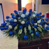 Large blue and white floral casket spray on a wooden casket