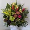 Tropical flower arrangement in a white pedestal vase with pink and green blooms