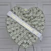 Heart-shaped money display with a white ribbon and small flower accent