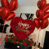 Heart-shaped rose arrangement with red balloons and a Happy Birthday sign