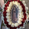 Oval bouquet of red and white roses around a religious image