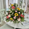 Mixed bouquet with sunflowers, pink carnations, and white daisies in a glass vase