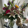 Mixed bouquet with lilies, roses, and purple flowers in a glass vase