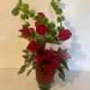 Red roses arranged in a glass vase with a red ribbon